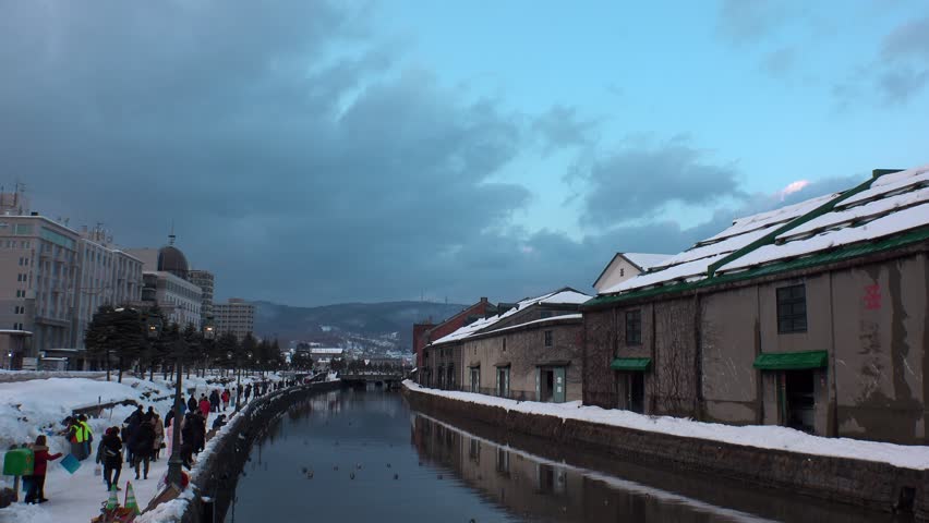 OTARU, HOKKAIDO, JAPAN - FEBRUARY 2020 : Sunset view of OTARU CANAL in winter snow season. Popular tourist destination for Japanese and foreign visitors. Time lapse shot, dusk to night.