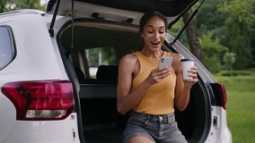 African American woman sitting trunk car automobile auto smile using mobile phone smartphone girl coffee fun social media technology internet female holding cup driver outside enjoy network transport - Powered by Shutterstock - Get 15% off with code: PIKWIZARD15
