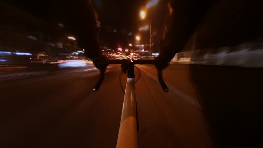 Cycling at night is a rapid time lapse through the streets of the city in first person view. The theme is urban transportation on sports bikes in downtown. Long exposure times form light trails.