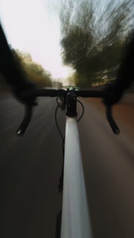 Vertical cycling is fast time-lapse through streets of city with first-person camera capturing. Theme of urban transportation on sports bikes in downtown. The long exposure time creates light trails.