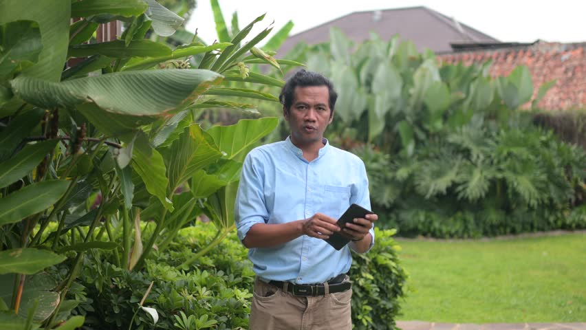 A Southeast Asian man opens his wallet to reveal a stack of 100,000 rupiah bills. Ideal for finance, lifestyle, or cultural projects showcasing currency and everyday life.