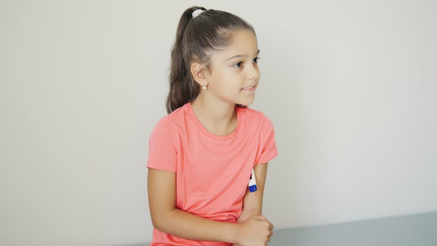 A young girl is preparing for her vaccination while wearing a bright tshirt, symbolizing health awareness and community engagement