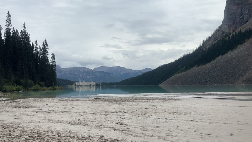 Lake Louise With Luxury Hotel In Distance, Surrounded By Mountains At Banff National Park, Alberta, Canada. wide shot