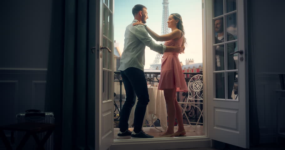 Caucasian Man and Woman Sway to Music on a Balcony Overlooking Paris and Eiffel Tower. Their Dance Becomes a Beautiful Celebration of Love and Connection. Couple on a Honeymoon Trip to France