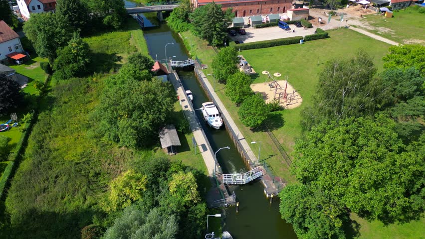 canal lock sluice being used by boats on a sunny summer day in germany Himmelpfort countryside Brandenburg. Majestic aerial view flight wide orbit overview drone