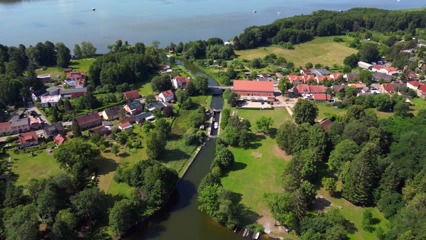 canal lock sluice being used by boats on a sunny summer day in germany Himmelpfort countryside Brandenburg. Smooth aerial view flight drone top down Above view