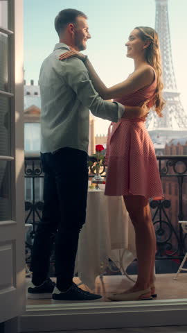 Vertical Screen: Young Couple Dances on a Parisian Balcony, Their Movements Light and Joyful Against the Backdrop of the Eiffel Tower. Romantic Setting Adds Magic to Their Intimate Relationship Moment