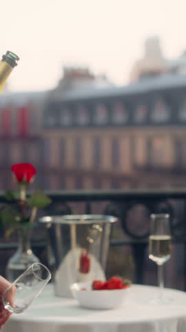 Vertical Screen: Anonymous Waiter Elegantly Pours Champagne on a Parisian Balcony, Overlooking the Eiffel Tower, Creating a Luxurious and Romantic Ambiance With Strawberries and a Rose on the Table