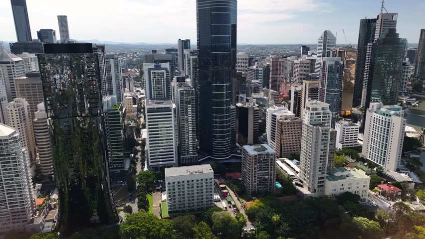 Skyscrapers and tall buildings in Brisbane CBD, drone pull back over green city park. Australia