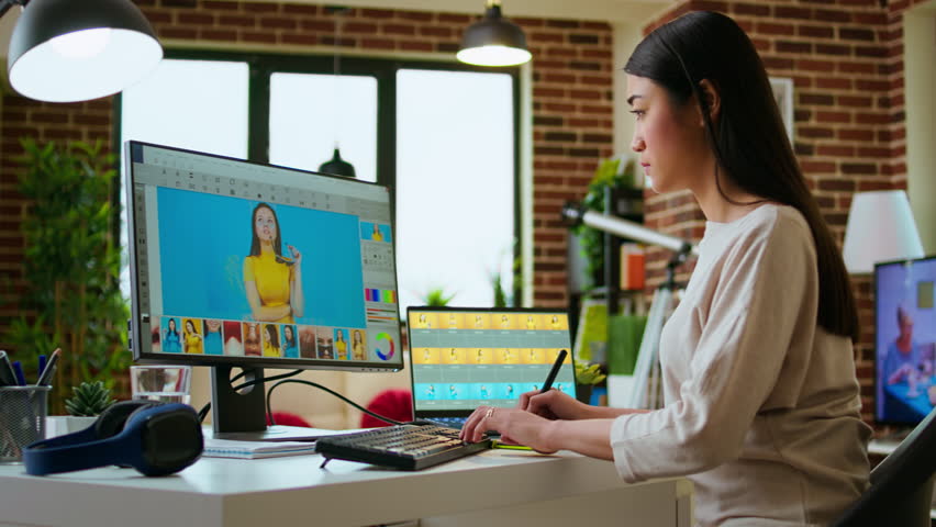 Asian creative woman edits photos using professional design software in a modern home office. Working with digital tools in the graphic design industry, retouching techniques. Camera A.