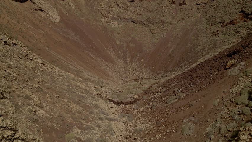 Dronie of volcano crater. Aerial view of volcano. Interior of a volcanic crater and lava outlet area. Canary Islands. Spain.