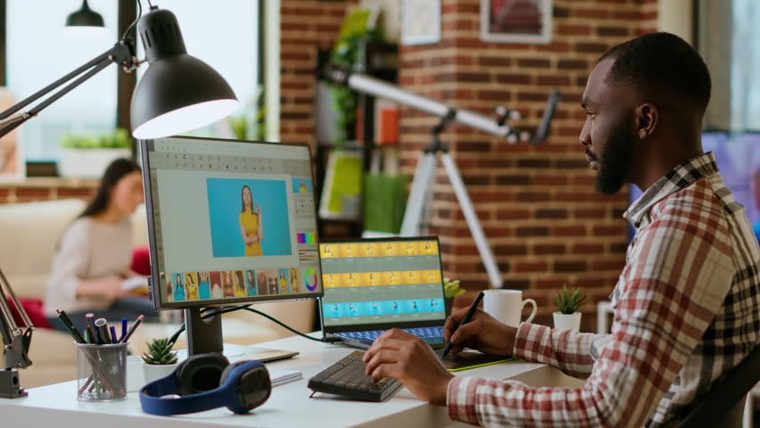 African american photo editor retouches images on his computer in a tech inspired workspace. Man does freelance tasks for photo retouching and digital art, media and graphic design sectors. Camera B. - Powered by Shutterstock - Get 15% off with code: PIKWIZARD15