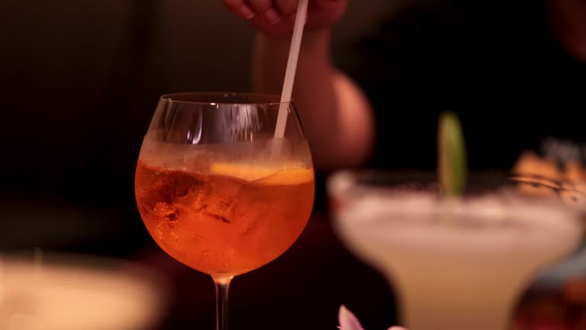 Hand stirring cocktail in a dimly lit bar