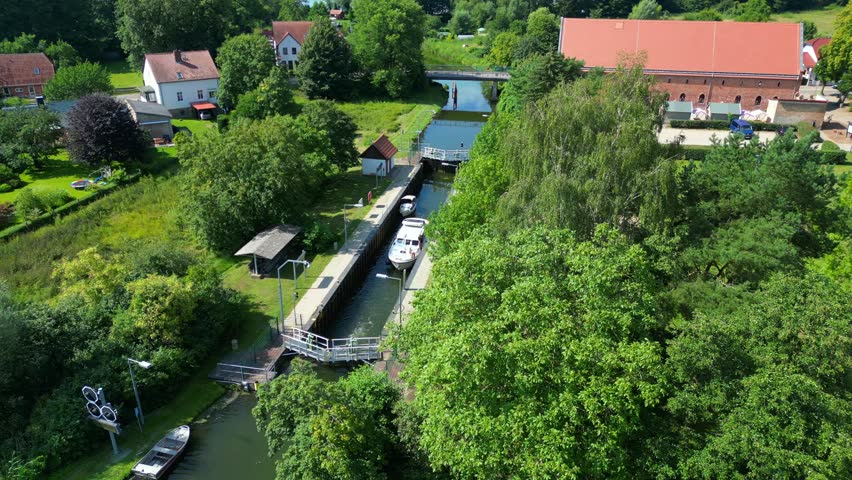 canal lock sluice being used by boats on a sunny summer day in germany Himmelpfort countryside Brandenburg. Great aerial view flight panorama orbit drone