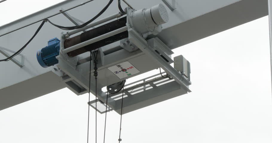Electric hoisting machine moving overhead from the left to the right side of the frame.