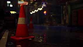 A red traffic cone sits atop a wet street in a bright neon-lit Asian city on a rainy night. - Powered by Shutterstock - Get 15% off with code: PIKWIZARD15