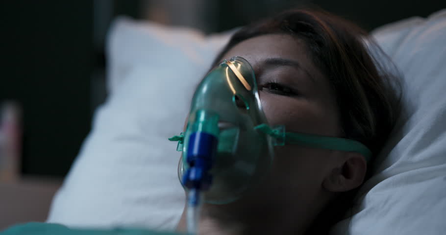 Young patient waking up suddenly in hospital bed with oxygen mask.
