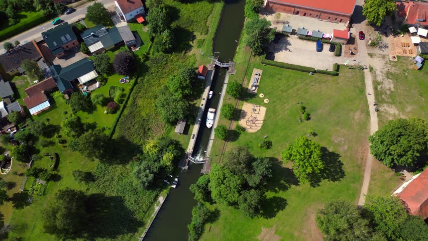 canal lock sluice being used by boats on a sunny summer day in germany Himmelpfort countryside Brandenburg. Amazing aerial view flight drone camera pointing down