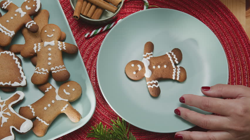 Making Christmas cookies - gingerbread men,  a woman is decorating cookies with royal icing.