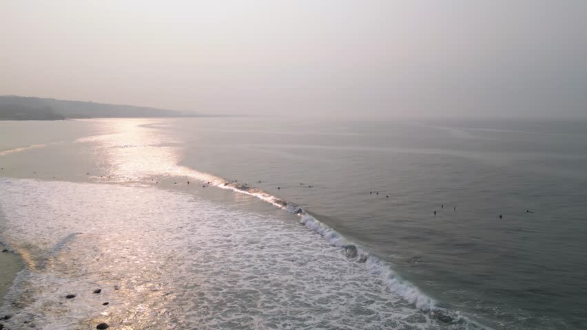 El Salvador, La Libertad beach, aerial view of the surf zone early in the morning with many surfer persons in the water trying to catch a wave - panoramic view