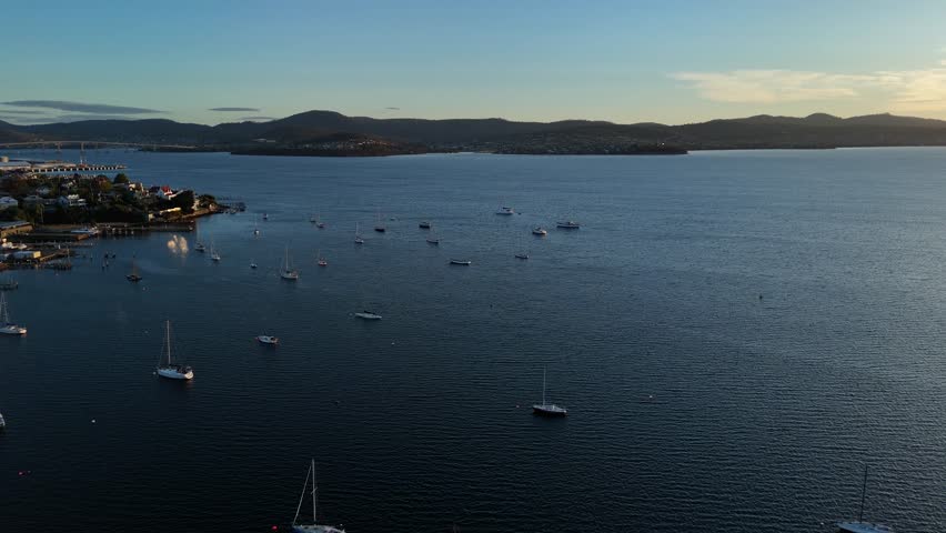 Boats moored at sunset, Hobart city, Tasmania in Australia. Aerial drone orbiting