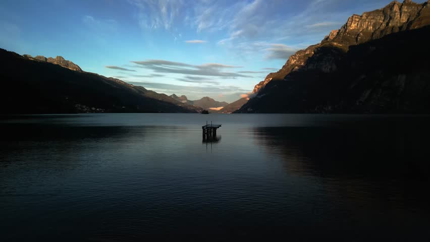 wooden pier standing on a mountain lake in Switzerland. Dawn, rays of sunlight. A lake surrounded by mountains. Dramatic dawn. high quality video