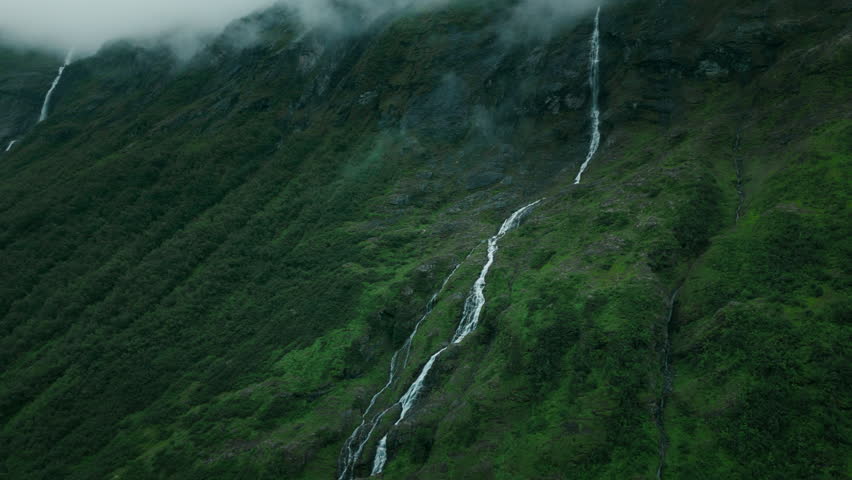 Aerial establishing shot of a waterfall running down a mountainside in Norway