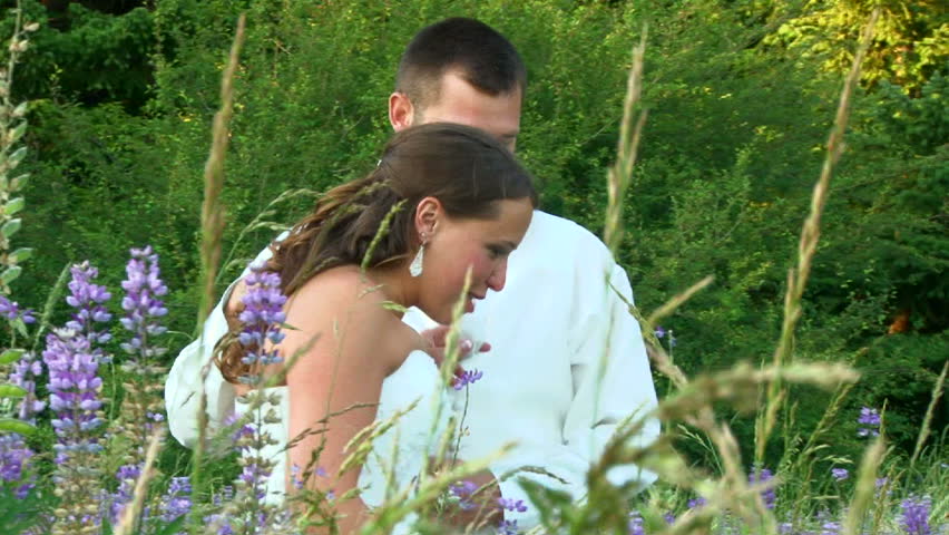 Model released bride and groom walk through flower field together on their