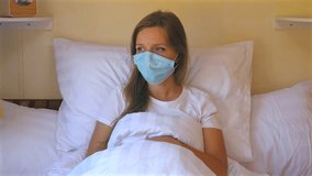 Woman lying in bed and wearing protective face mask, looking thoughtful and concerned, in cozy bedroom setting, Health and Safety. - Powered by Shutterstock - Get 15% off with code: PIKWIZARD15