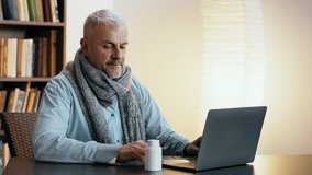 Sick Older man sitting at a table with a laptop and a bottle of supplements in a cozy indoor setting during the daytime - Powered by Shutterstock - Get 15% off with code: PIKWIZARD15