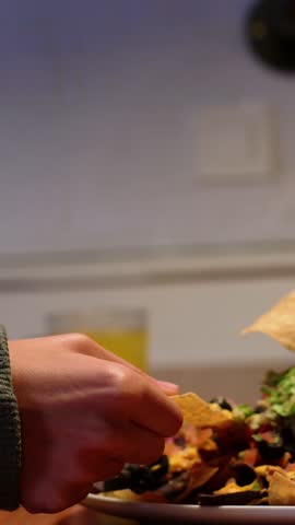 Latina girl eating Mexican nachos with guacamole with her hands. 