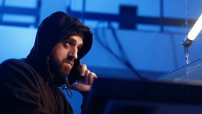 Hacker hiding in underground bunker, chatting with friend in telephone call, anxious after stealing data from victims using computer virus, scared about being caught by police, camera A close up - Powered by Shutterstock - Get 15% off with code: PIKWIZARD15