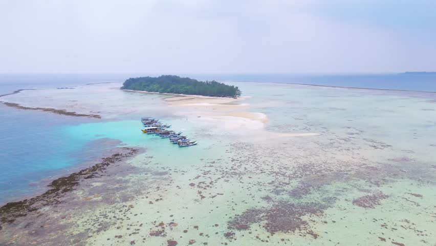 An aerial view of a tropical island in the middle of the sea that is so vast with very beautiful sea water