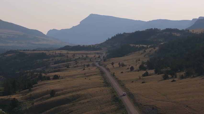 A camper drives down a scenic road in Wyoming