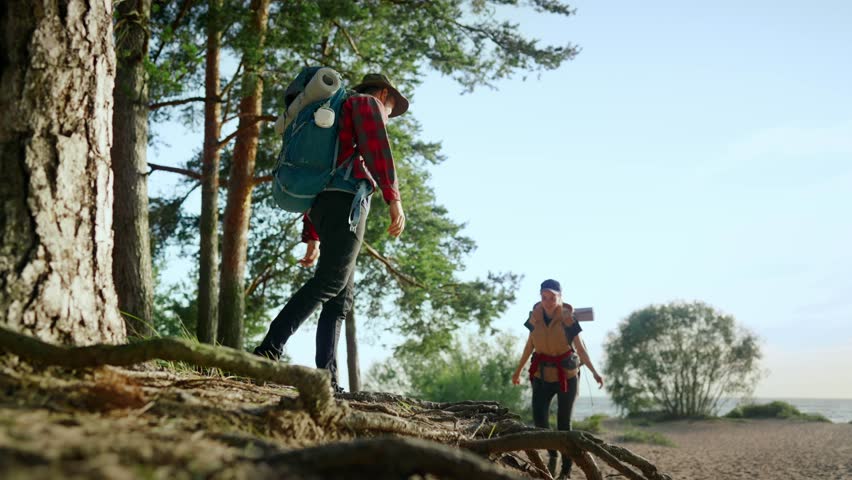 Local tourism and traveling in nature, man and woman with backpacks walking. Two tourists strolling in beautiful forest on shore of river or lake, help and support of friends, friendship and solitary