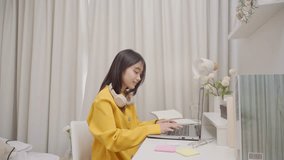Asian girl student learning online class study with teacher in house. Teenage woman smiling, taking notes and using laptop computer device remote study on table in bedroom at home. - Powered by Shutterstock - Get 15% off with code: PIKWIZARD15