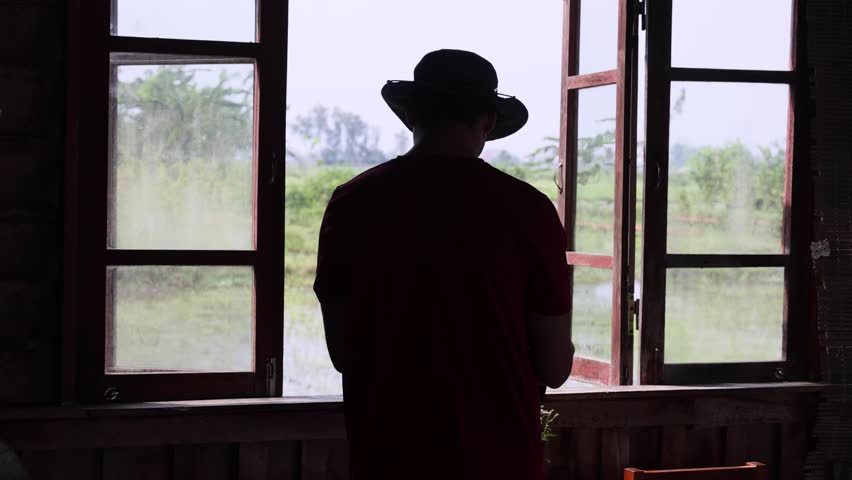 The silhouette of an unrecognizable male traveler against the backdrop of an ancient wooden window.