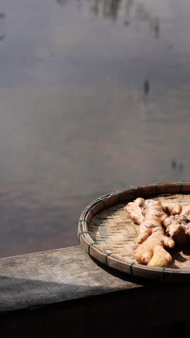 Freshly harvested ginger root on a bamboo plate against a water background. Ginger for cooking.