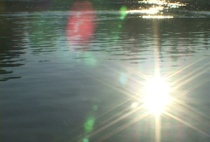 River in Oregon reflects sun and solar flare.