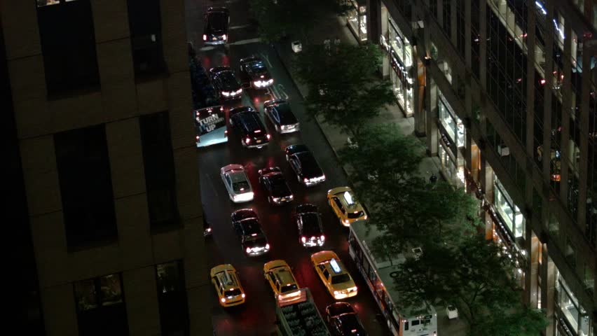 Stunning timelapse of New York City traffic at night, showcasing the bustling energy of urban life with moving cars, taxis, buses, and pedestrians under the city lights.