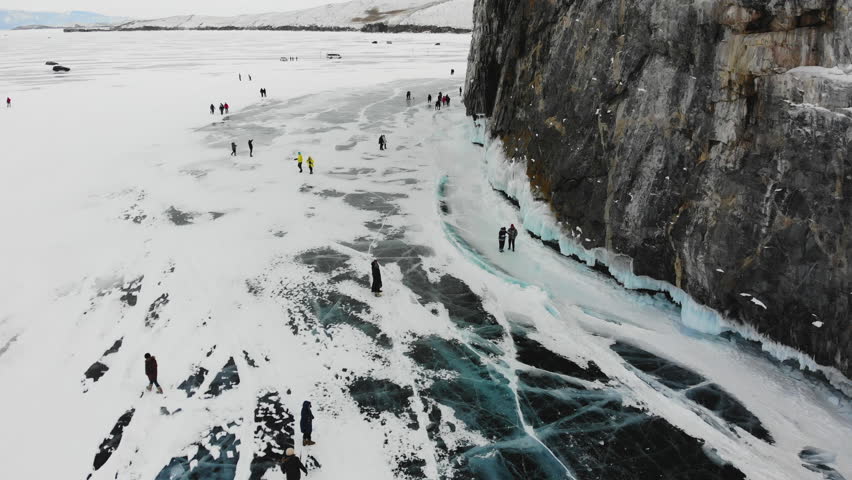Tourists walk on the ice of the frozen Lake Baikal. Winter trip