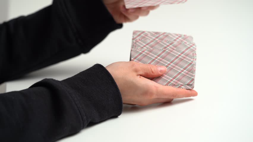 Hands of a young woman shuffling cards at the table for the next game. Entertainment concept, having fun, card board games