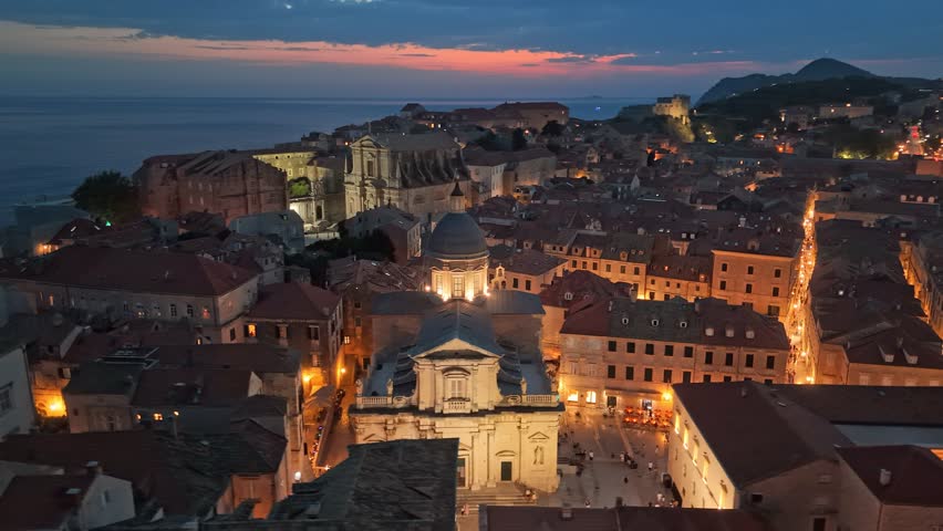 Aerial Nighttime View of Dubrovnik's Old Town, Croatia. Fly around Cathedral of the Assumption of the Virgin Mary in Dubrovnik with city lights at sunset
