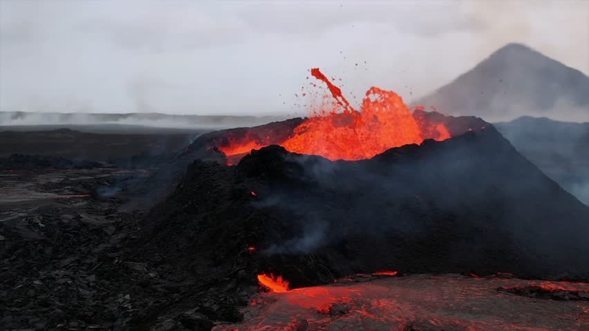 A volcano erupts in Iceland, spewing molten lava and ash, with lava flowing down the rugged volcanic landscape. Smoke and ash rise into the sky.