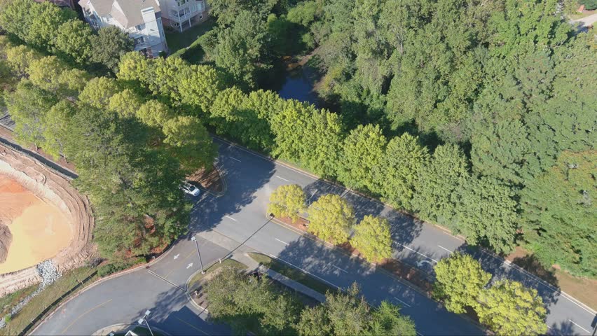 aerial footage of a silky green lake surrounded by lush green trees, grass and plants and office buildings at Lenox Park in Brookhaven Georgia USA