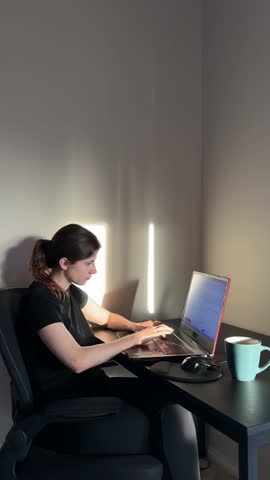 Young woman working remotely struggles with a headache, feeling stressed and exhausted while using her laptop at home