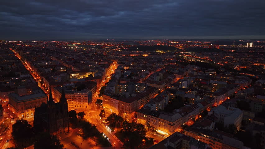 Warm lights illuminate the spires of St. Vitus Cathedral as dusk settles over Prague, highlighting the city