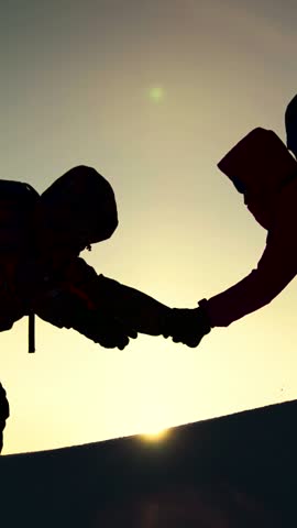 Travelers climb one after another on rock. Path to success through difficulties Concept. Teamwork of business people. Climbers silhouettes stretch their hands to each other, climbing to top of hill.