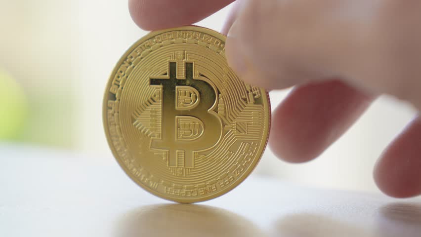 Slow motion shot of a bitcoin cryptocurrency coin spinning in a persons fingers