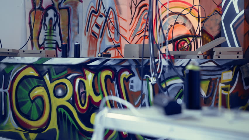 Graphic grunge graffiti art on walls in derelict building, concept of alternative lifestyle. Panning shot of ghetto abandoned building used as headquarters by teenagers hanging out